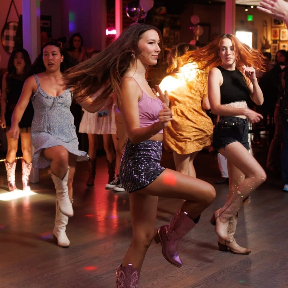 Guests line dancing in cowboy boots on the Westwood dance floor