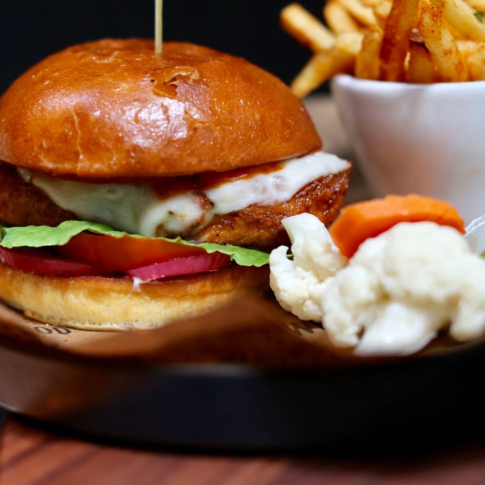 Cheeseburger with lettuce, tomato, onion, and sauce served with fries, carrots, pickles, and cauliflower.